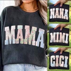 Puede incluir: Sudadera negra con la palabra "MAMA" en letras de patchwork, con diseños florales y cuadros. Se muestran sudaderas negras adicionales con las palabras "NANA", "MIMI" y "GIGI" en diseños similares.