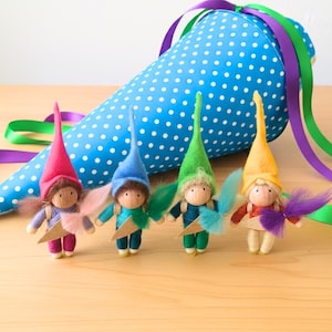 Vier bunte, handgefertigte TiTa-Tüte Schulwichtel in Rot, Blau, Grün und Pink mit spitzen Filzhüten, einer Schultüte und einem aufgesetztem Schlranzen stehen nebeneinander – ideal als Geschenk zur Einschulung und Glücksbringer für Klausuren sowie Abitur