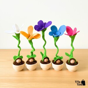 Das komplette Set der Wurzel-Wichtel von TiTa-Tüte: Fünf handgefertigte Blumenkinder aus Filz in Holztöpfchen. Die Farben Weiß (Schneeglöckchen), Orange (Ringelblume), Lila (Veilchen), Blau (Vergissmeinnicht) und Pink (Wildrose) stehen nebeneinander