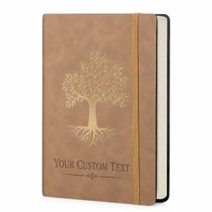 May include: A tan notebook with a textured cover featuring a gold foil embossed tree design in the center. Below the tree, the text "YOUR CUSTOM TEXT" is printed in a dark font. A vertical gold elastic band secures the notebook closed.