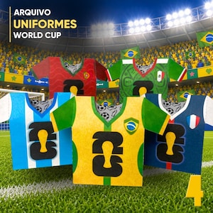 Peut inclure: Plusieurs maillots de football en papier colorés, représentant des pays comme le Brésil, l'Argentine et la France, sont présentés sur un terrain vert. Chaque maillot porte un grand numéro. En arrière-plan, un stade rempli de spectateurs.