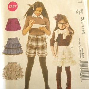Può includere: Modello di cucito McCall's per abbigliamento da ragazza, con illustrazioni di pantaloncini e gonne. Il modello include il testo "EASY" e la taglia CCE (3-4-5-6). La copertina mostra un disegno di due ragazze che indossano i vestiti.