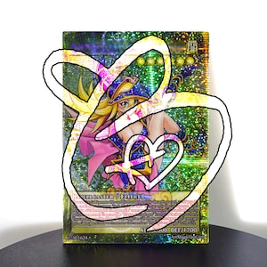 May include: A holographic trading card featuring a female anime character in a blue and pink outfit. The card has text at the bottom indicating an attack power of 2000 and a defense of 1700. The card is labeled as a Spellcaster/Effect card.