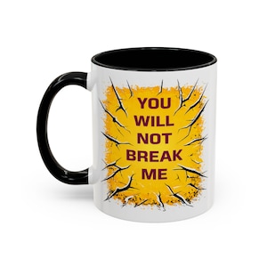 以下が含まれることがあります： 黒いハンドルと内側を備えた白いセラミックマグ。マグには、「YOU WILL NOT BREAK ME」というテキストが、黒いギザギザの線が入った黄色の背景に、栗色の文字で表示されています。