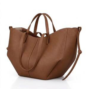 Puede incluir: Un bolso tote marr&oacute;n con dos asas cortas y una correa larga y ajustable para el hombro. El bolso tiene un dise&ntilde;o estructurado con una abertura ancha y un interior neutro. El bolso est&aacute; hecho de un material texturizado.