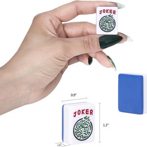 Puede incluir: Una ficha de Mahjong blanca y azul con el texto rojo JOKER y un gr&aacute;fico circular verde. La ficha mide 2,29 cm de ancho, 3,05 cm de alto y 1,27 cm de profundidad, tal como indican las medidas visibles en la imagen.