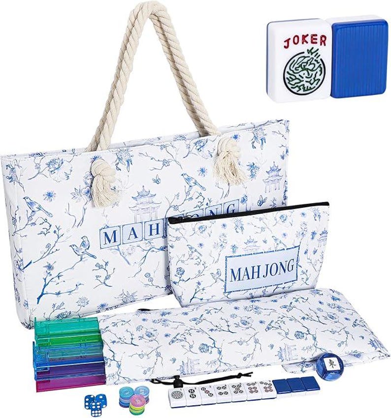 Puede incluir: Un bolso tote blanco y un estuche a juego con cremallera con un patr&oacute;n floral y de p&aacute;jaros en azul y el texto MAH JONG. Incluye un juego de soportes para fichas transl&uacute;cidos de colores, fichas blancas con reverso azul y fichas redondas.