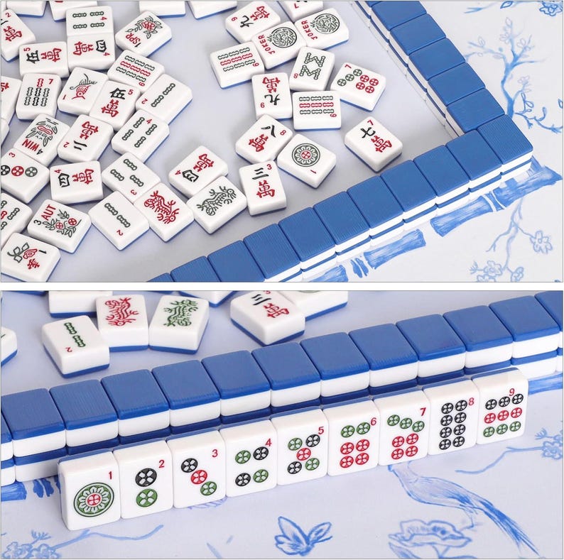 Puede incluir: Un conjunto de fichas de mahjong blancas con el reverso azul, que presentan varios s&iacute;mbolos, caracteres y n&uacute;meros grabados en rojo, verde y negro. Algunas fichas est&aacute;n dispuestas en filas ordenadas, mientras que otras est&aacute;n esparcidas sobre una superficie con motivos florales azules.