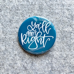 May include: A teal blue button with the text "Y'all ain't right" in white cursive lettering.