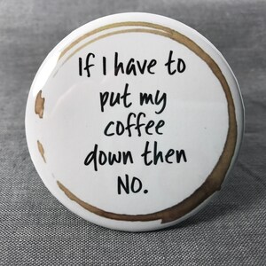 May include: White round button with a brown coffee ring stain. The button has black text that reads "If I have to put my coffee down then NO."