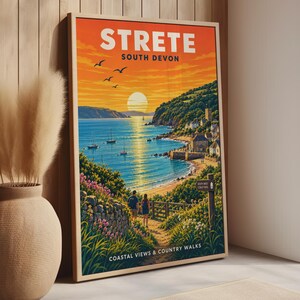 May include: A framed travel poster featuring a coastal landscape of Strete, South Devon. The illustration depicts a sunset over the ocean with sailboats, a village on the hillside, and two people walking on a path. Text reads STRETE SOUTH DEVON.