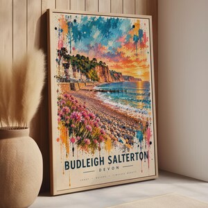 Könnte beinhalten: Ein gerahmter vertikaler Wandkunstdruck mit einer Aquarell-Landschaft von Budleigh Salterton, Devon. Die Szene zeigt einen Kieselstrand, rosa Wildblumen, Küstenklippen und einen Sonnenuntergangshimmel mit leuchtenden blauen, orangen und rosa Farbspritzern.