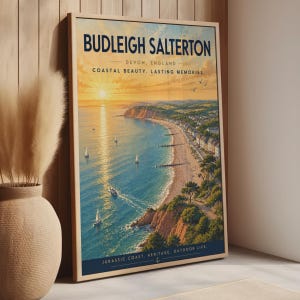 Puede incluir: Un póster de viaje enmarcado que muestra un paisaje costero de Budleigh Salterton, Devon, Inglaterra. La obra representa una puesta de sol sobre el océano con veleros, acantilados y un pueblo junto a la playa. El texto incluye 'BUDLEIGH SALTERTON'.