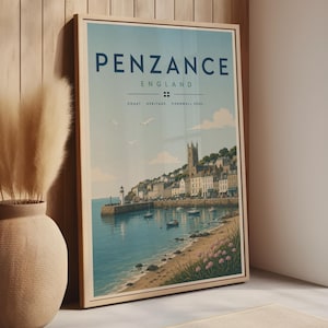 May include: A framed vertical wall art print featuring a coastal scene of Penzance, England. The illustration depicts a harbor with boats, a lighthouse, and town buildings under a light blue sky. Text reads: PENZANCE ENGLAND COAST HERITAGE CORNWALL SOUL.