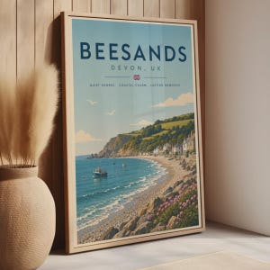 May include: A framed travel poster featuring a coastal landscape of Beesands, Devon, UK. The print displays the text BEESANDS, DEVON, UK, a small Union Jack, and the words QUIET SHORES, COASTAL CHARM, LASTING MEMORIES above a blue sea and hills.
