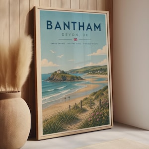 Puede incluir: Un póster de viaje enmarcado que muestra un paisaje costero de Bantham, Devon, Reino Unido. La impresión presenta una playa de arena, océano azul, una isla rocosa con una casa y dunas de hierba. El texto dice: BANTHAM, DEVON, UK, SANDY SHORES, ROLLING TIDES, TIMELESS BEAUTY.