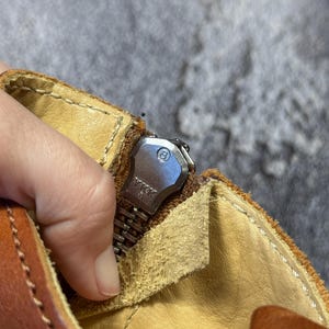 May include: Close-up of a brown leather boot with a silver zipper. The zipper is partially open, revealing the interior lining. The zipper pull is marked with the letters "YKK". The boot has visible stitching and a worn appearance.