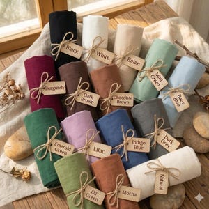 Puede incluir: Una colecci&oacute;n de muestras de tela enrolladas en varios colores, incluyendo negro, blanco, beige, verde menta, azul beb&eacute;, burdeos, marr&oacute;n oscuro, marr&oacute;n chocolate, verde esmeralda, lila, azul &iacute;ndigo, gris oscuro, verde aceite, moca y natural.
