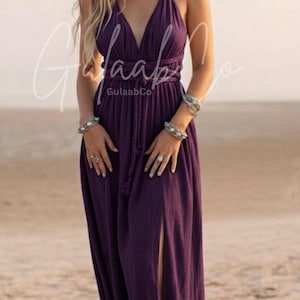 Könnte beinhalten: Ein bodenlanges Maxikleid in Dunkelviolett mit Neckholder-Ausschnitt und geflochtenen Trägern, tiefem V-Ausschnitt, tailliertem Schnitt mit geflochtenem Bindegürtel und Seitenschlitz. Der Text GulaabCo und www.gulaabco.com ist sichtbar.