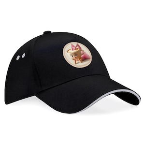 Pode incluir: Boné de beisebol preto com acabamento branco na aba. O boné apresenta um patch circular com uma imagem de desenho animado de um bebê em uma xícara de chá usando um tutu rosa e um laço. O boné tem uma aba curva e um botão na parte superior.