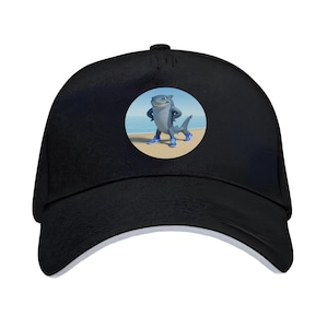Pode incluir: Boné de beisebol preto com um gráfico circular de um tubarão de desenho animado em uma praia, usando tênis azuis. O tubarão está com os braços cruzados e sorrindo. O boné tem uma aba curva e um botão no topo.