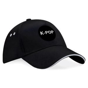 May include: Black baseball cap with a white trim on the brim and the text "K-POP" in a white circle on the front. The cap has a curved bill and a button on top. Two white dots are on the side of the cap.