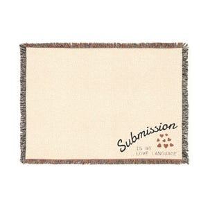 May include: Cream-colored woven throw blanket with a fringed edge. The blanket features the text "Submission IS MY LOVE LANGUAGE" in black script with small red heart graphics.