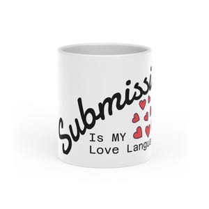 May include: White ceramic mug with the words "Submission Is MY Love Language" in black script. Red heart graphics are next to the words. The mug is cylindrical and has a glossy finish.