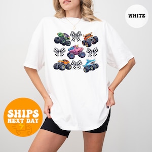 A woman wearing a white t-shirt with a graphic design of colorful monster trucks and checkered flags.