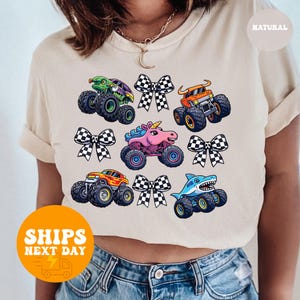 A person wearing a white t-shirt with a graphic design of colorful monster trucks and checkered flags.
