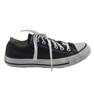 May include: Black low-top canvas sneaker with white laces and a white rubber toe cap. The shoe has a white rubber sole with a black stripe and a textured toe bumper. The sneaker is a classic, casual style.