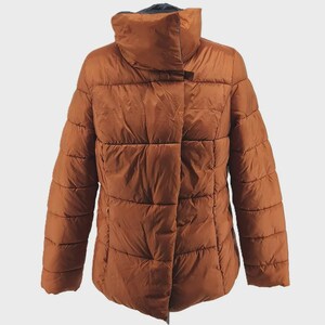 May include: A brown puffer jacket with a high collar. The jacket has a quilted design and a zipper closure. The sleeves are long and the jacket is a solid color. The jacket is designed for cold weather.