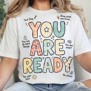 May include: White t-shirt with the words "YOU ARE READY" in colorful, playful lettering. The design includes stars, hearts, and other decorative elements, along with phrases like "Test Day" and "No stress."
