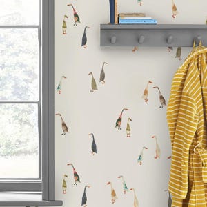 May include: A wall decorated with a repeating pattern of watercolor geese in various colors. A gray shelf with books and a yellow striped robe hanging on the wall are also visible. A window frame is on the left.