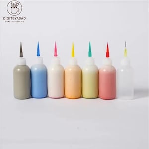 May include: A row of seven squeeze bottles with colorful contents and pointed tips. The bottles are filled with various colors, including gray, blue, white, orange, yellow, pink, and clear. The tips are in matching colors.