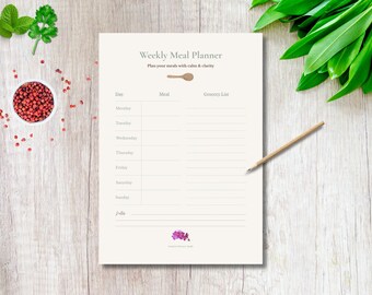 May include: A Weekly Meal Planner on a wooden surface. The planner has a beige background with the text "Weekly Meal Planner" and "Plan your meals with calm & clarity". A wooden pencil rests on the right side of the planner.