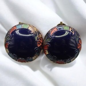 Puede incluir: Un par de pendientes redondos vintage con un centro de esmalte azul oscuro. Los pendientes presentan diseños florales y geométricos coloridos en rojo, naranja, verde y azul. El metal tiene un tono dorado.
