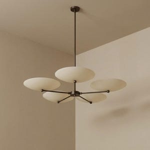 May include: A modern, five-light chandelier with a dark bronze finish. The fixture features five off-white, saucer-shaped shades extending from a central hub. The chandelier is suspended from the ceiling by a single rod.