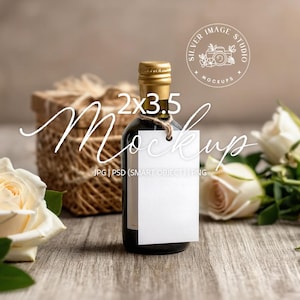 May include: A dark glass bottle with a gold cap and a blank white tag, tied with twine. The bottle is 2 x 3.5 inches. A woven basket and white roses are in the background, on a wooden surface. The image has a soft, natural aesthetic.