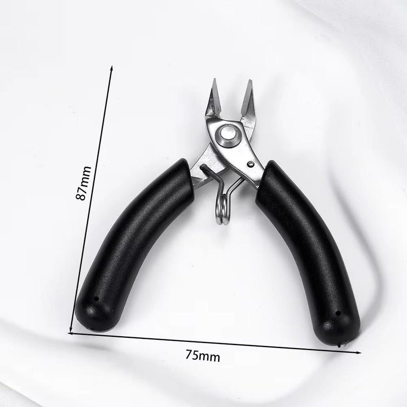 May include: A pair of silver metal pliers with black rubber handles. The pliers are 3 inches long and 3.4 inches high. The tool has a spring and is designed for cutting or gripping small objects.