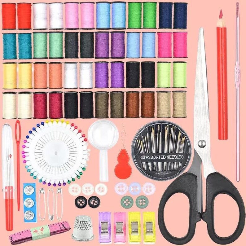 May include: A sewing kit with a variety of colorful thread spools, needles, scissors, pins, buttons, and a measuring tape. The kit includes a thimble, needle threader, and assorted sewing clips. The background is a light pink.