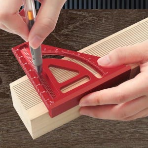 May include: A red aluminum speed square is used to mark a wooden block with a pen. The square has measurement markings in inches and degree angles. The wooden block is light brown, and the background is a dark brown.