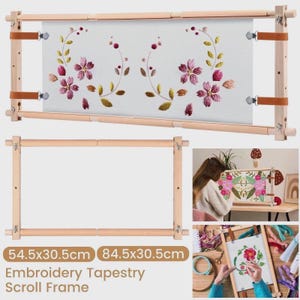 May include: A wooden embroidery tapestry scroll frame with a floral design. The frame has adjustable wooden bars and leather straps. The embroidered fabric features pink flowers and green leaves. The frame dimensions are 54.5 x 30.5 cm and 84.5 x 30.5 cm.