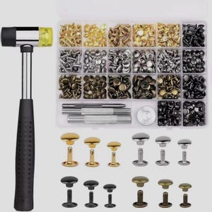 May include: A leathercraft kit featuring a black and silver hammer with a yellow striking head, a clear plastic organizer filled with various metal rivets, and a selection of decorative rivets in gold, silver, and black.