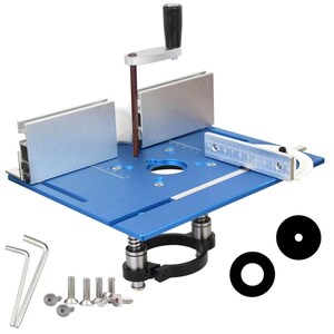 May include: A blue router table with silver metal components, including a fence, handle, and measuring guide. The table includes a black handle, a black ring, and two black circular inserts. Also included are screws and Allen wrenches.