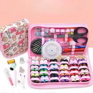 May include: A pink sewing kit with various sewing supplies, including spools of thread, scissors, needles, and a measuring tape. The kit is open, revealing the organized contents. A separate, matching pouch is visible.