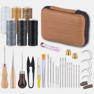 May include: A sewing kit with various tools and supplies. Includes spools of white, gray, black, and tan thread, needles, scissors, thimbles, a measuring tape, and a wooden-look case. The kit is designed for sewing and crafting projects.