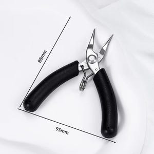 May include: Needle-nose pliers with black handles, measuring 3.5 inches long and 3.5 inches wide. The pliers are made of silver metal and are designed for precision work. The image shows the pliers open, with the tips pointing upwards.