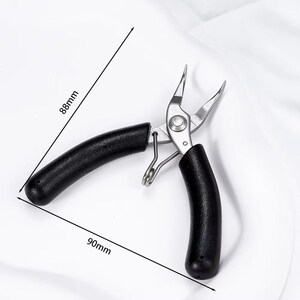 May include: Needle-nose pliers with black handles, measuring 90mm long and 88mm wide. The pliers are made of silver metal and are designed for precision work. The handles are curved for a comfortable grip. The tool is open, ready for use.