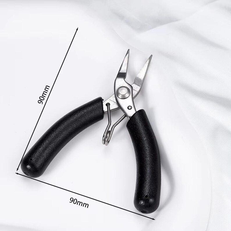 May include: A pair of silver metal pliers with black rubber handles, each measuring 90mm in length. The pliers have pointed tips and a spring mechanism. The tool is designed for precision work.